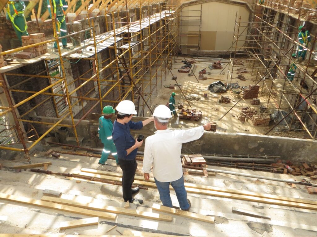 A group of construction professionals reviewing blueprints and building plans at a residential job site.