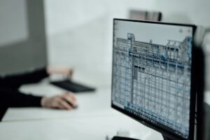 A group of construction professionals reviewing a 3D building model on a tablet at a job site.