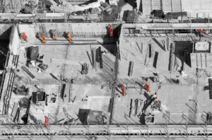 Technicians reviewing a 3D building model on a large screen in a construction planning room.